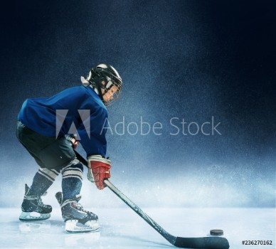 Picture of Little boy playing ice hockey at arena A hockey player in uniform with equipment over a blue background The athlete child sport action concept